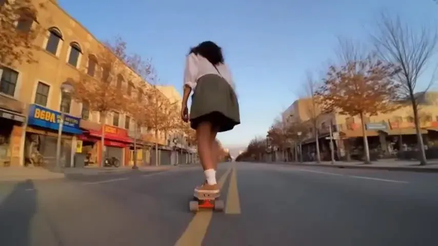 Wan 2.5 street recipe illustration: a girl longboarding down the middle of an empty autumn street at golden hour
