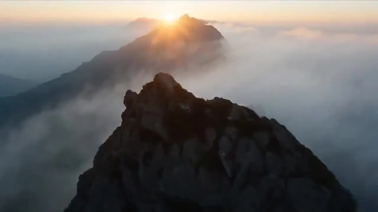 Seedance image to video prompt illustration: a sea of clouds rolling over a jagged mountain ridge at sunrise